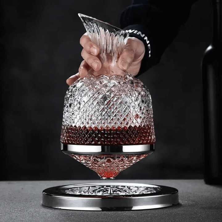 Obrotowa kryształowa karafka do wina, elegancki i nowoczesny design, srebrne wykończenie, na białym tle.