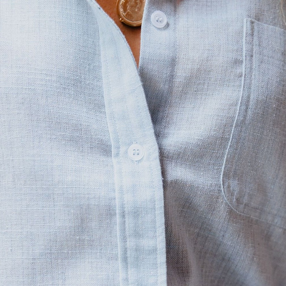 Jasnoniebieska damska lniana koszula, luźny krój, długie rękawy, klasyczny kołnierz, proste guziki dla swobodnej elegancji.