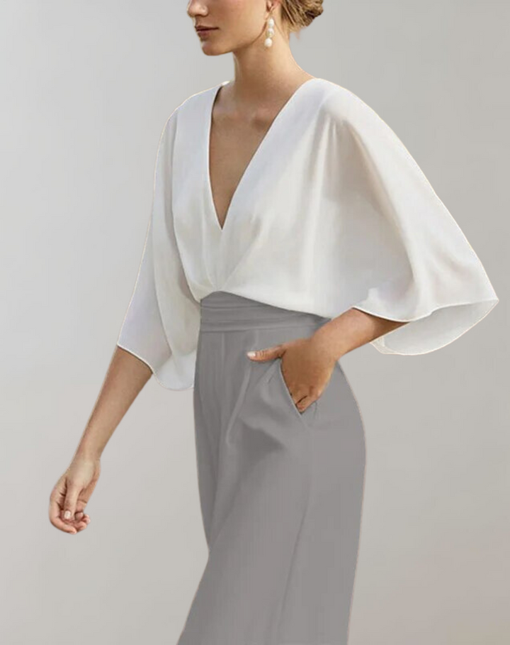 Zwiewny kombinezon damski z rękawami motylkowymi, dekoltem w serek, podkreśloną talią i szerokimi nogawkami, elegancki i wygodny.