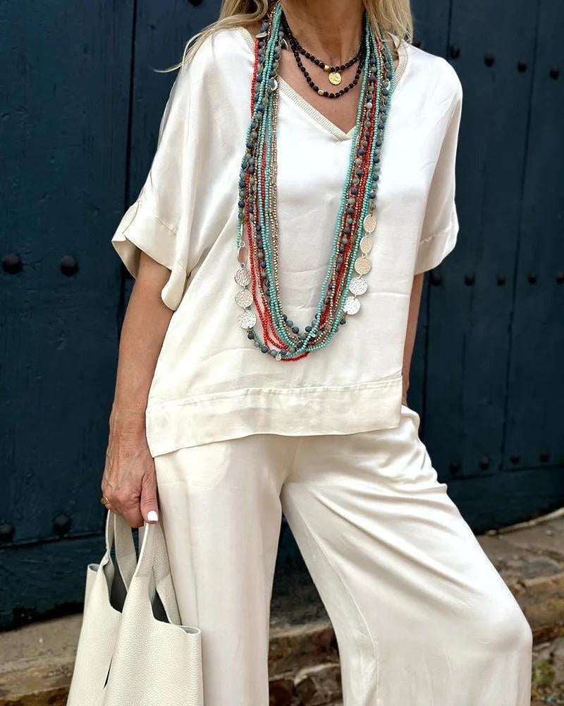 Szykowany zestaw dla kobiet: misternie skrojona bluzka i dopasowane spodnie dla eleganckiego i wyrafinowanego wyglądu.