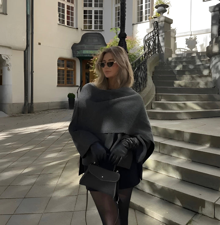 Damski elegancki jesienny płaszcz-peleryna, asymetryczny design w kolorze szarym, miękki materiał, nowoczesny i wygodny styl na chłodne dni.