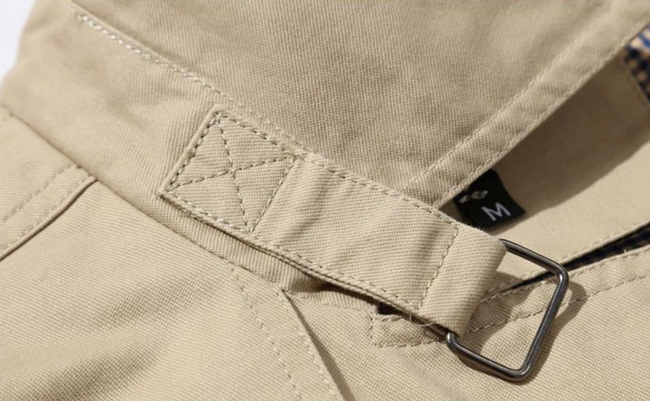 Elegancki męski płaszcz trenczowy o strukturalnym kroju, gładkiej podszewce, wyraźnych naramiennikach i wyrafinowanym podwójnym zapinaniu.