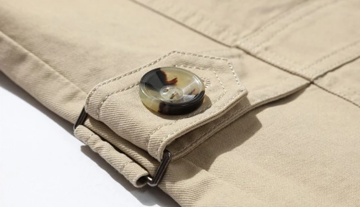 Elegancki męski płaszcz trenczowy o strukturalnym kroju, gładkiej podszewce, wyraźnych naramiennikach i wyrafinowanym podwójnym zapinaniu.