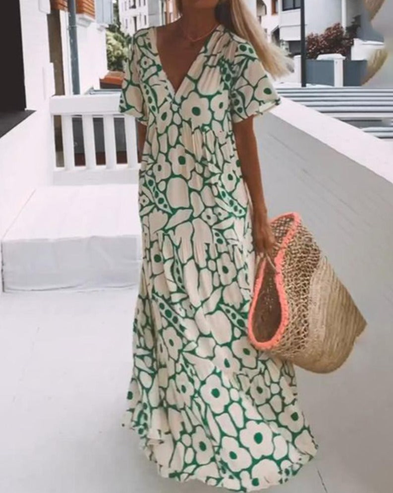 Długa zwiewna sukienka z kwiatowym wzorem w kolorze zielonym, z krótkimi, falbaniastymi rękawami i dekoltem w szpic, idealna na lato.