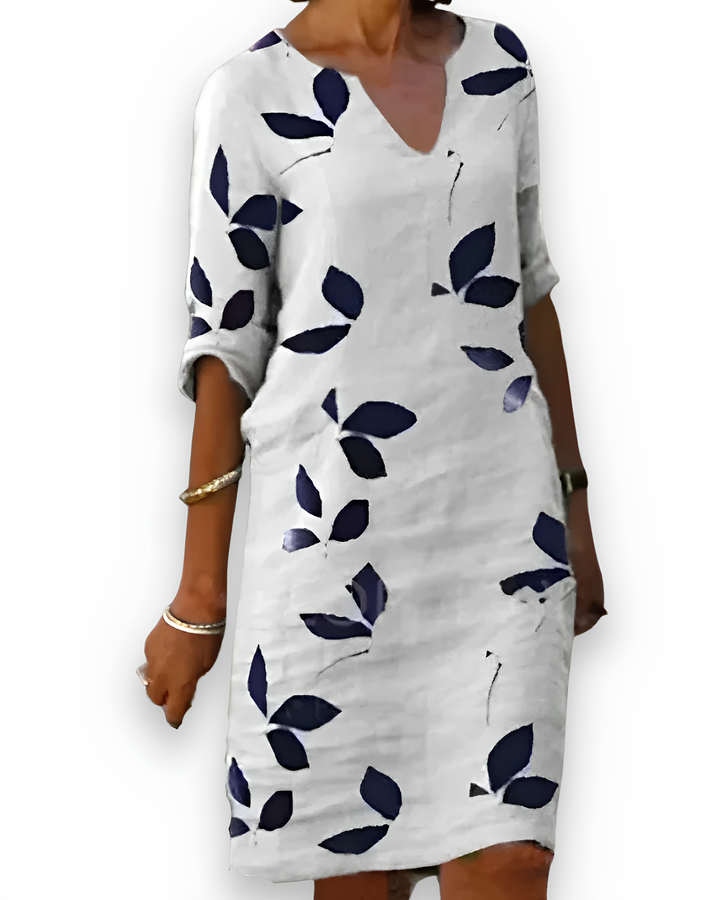 Damska długa zwiewna sukienka, lekki materiał, dekolt w serek, wzór w liście, zapewniająca komfort i elegancki letni styl.